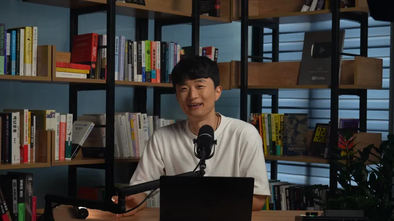 찍은 그대로의 한 장면 — 책장 앞 인물이 작게 보이는 넓은 화면